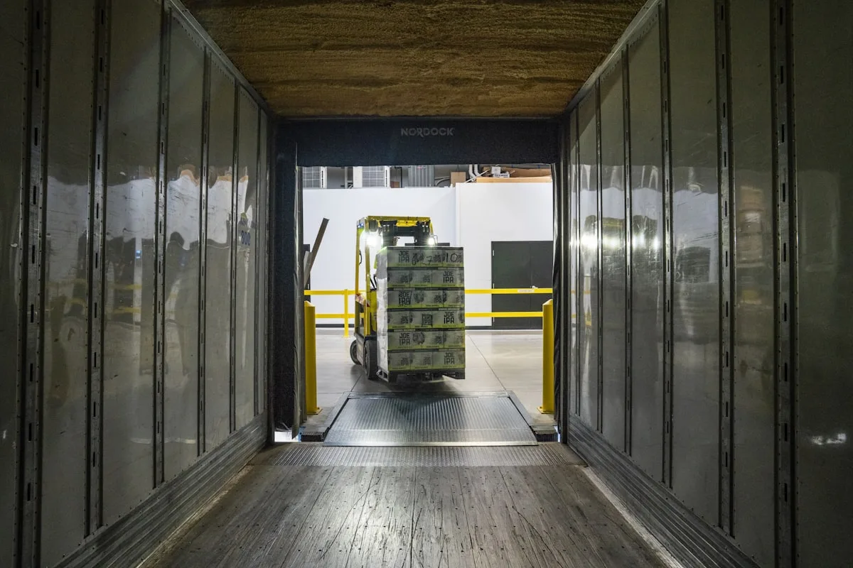 Forklift loading palletized cargo at a warehouse dock